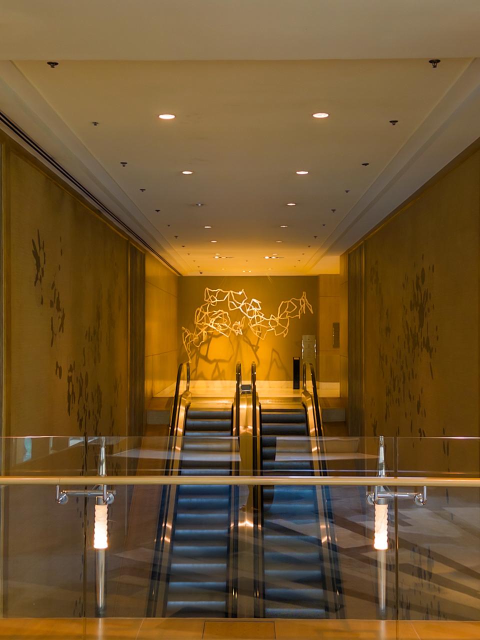 Escalator area at Shangri-La The Fort featuring artistic wall design and golden tones
